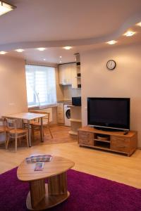 ein Wohnzimmer mit einem Flachbild-TV und einem Tisch in der Unterkunft Apartament Amber, Liepāja in Liepāja
