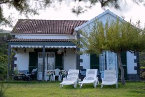 a group of white chairs in front of a house at Casa da Baía in Prainha de Baixo