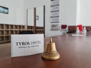 ハノーファーにあるタイロス ホテル ウント ガストハウス アム ヴァイデンダムの箱の横のテーブルに座る真鍮鐘