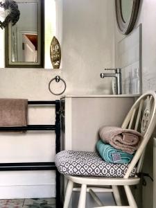a chair in a bathroom with a sink and a mirror at Ballygally Seaview and Garden Hideaway in Ballygalley