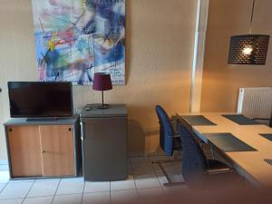 Zimmer mit einem Tisch mit Stühlen und einem TV in der Unterkunft Business Apartment near Neuss/Düsseldorf in Korschenbroich