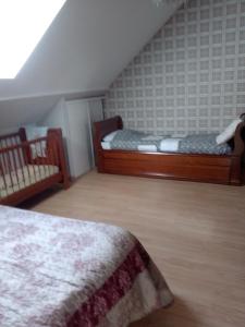 a attic bedroom with two beds and a crib at La longère in Épineu-le-Chevreuil