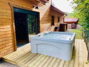 a hot tub sitting on a deck next to a house at Le Hygge Chalet Gérardmer-Spa in Anould