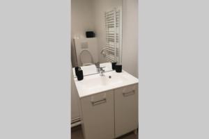 La salle de bains est pourvue d'un lavabo blanc et d'un miroir. dans l'établissement Bel appartement dans residence de standing neuve, à Châtel-Guyon