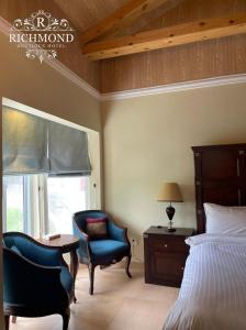 a bedroom with a bed and a chair and a window at Richmond Boutique Hotel in Nathia Gali