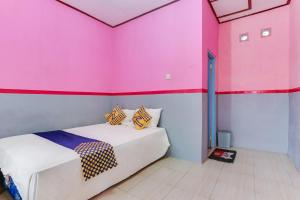 Habitación con 2 camas en una habitación con paredes de color rosa. en Ijen Traveller & Homestay en Banyuwangi