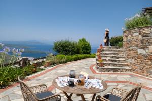 a patio with a table and chairs and a stone wall at Esperos Suites & Villas in Lafkos