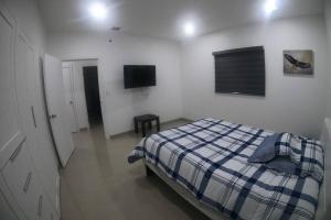 a bedroom with a bed and a tv on the wall at Paraíso en Rosarito a pie de la playa in Rosarito