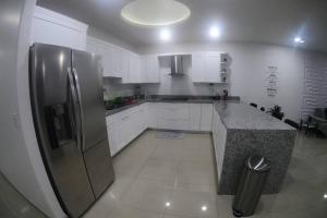 a kitchen with white cabinets and a stainless steel refrigerator at Paraíso en Rosarito a pie de la playa in Rosarito