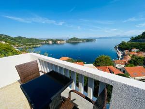a balcony with a table and chairs and a view of a lake at Guest House Ruža in Sobra