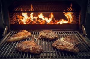 three pieces of meat are cooking on a grill at Pela Apartments in Sisi