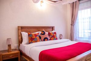 een slaapkamer met een bed met rode lakens en een raam bij Lost in Africa Arusha in Arusha
