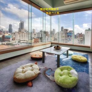 ein Wohnzimmer mit einem Tisch und großen Fenstern in der Unterkunft Hotel Blessings in Kaohsiung