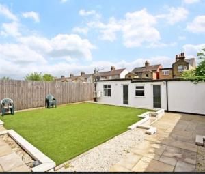 a backyard with a large lawn and a fence at Beautiful 6 Bedroom with spacious Lounge & Rooms Free parking in Erith