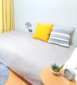Cama con almohada amarilla y mesa en Luxes Hiroshima2F ラクセス ヒロシマ2F, en Hiroshima