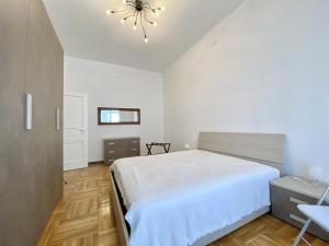 a white bedroom with a bed and a chandelier at CIT MA BEL in Cuneo