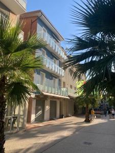 a tall building with palm trees in front of it at MANSARDA CASA GABRIELLA in Cattolica