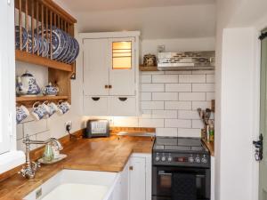 cocina con armarios blancos y encimera de madera en Michaelmass Cottage, en Whitby