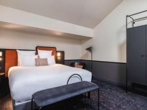 Pokój hotelowy z dużym łóżkiem i krzesłem w obiekcie Mercure Bordeaux Centre Gare Atlantic w mieście Bordeaux