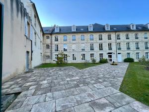 een binnenplaats voor een groot gebouw bij Le Monastère in Bayeux