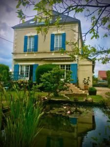 ein Haus mit blauen Fensterläden und einem Teich davor in der Unterkunft Les rêves d'Angèle in Crain