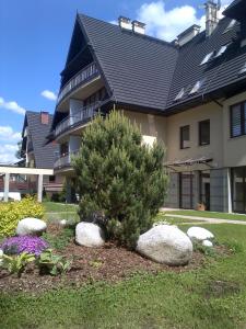 una casa con un árbol y rocas delante de ella en Apartament VIP, en Zakopane
