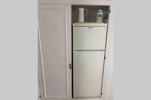 a white refrigerator in a kitchen next to a door at PUERTAS AL MAR in Cala en Blanes