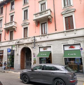 Hotel Fiorella Milano في ميلانو: سيارة متوقفة أمام مبنى وردي
