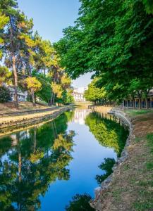a river with trees and a building in the background at MY HOME Trikala in Tríkala