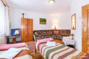 sala de estar con 2 camas y sofá en PENSIUNEA BORDÁS PANZIÓ, en Sfântu-Gheorghe