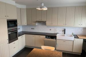 eine Küche mit weißen Schränken und einer Spüle in der Unterkunft Duplex Appartement Nokeredorp - Vlaamse Ardennen in Kruisem