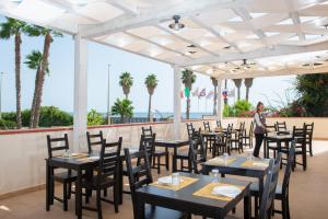 Eine Frau steht vor Tischen auf einer Terrasse in der Unterkunft Hotel President Sea Palace in Noto Marina