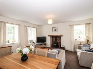 a living room with a table and a fireplace at Hilber Cottage in Ambleside