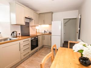 a kitchen with white cabinets and a wooden table at Hilber Cottage in Ambleside +10 photos