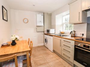 a kitchen with a wooden table and a table and a dining room at Hilber Cottage in Ambleside