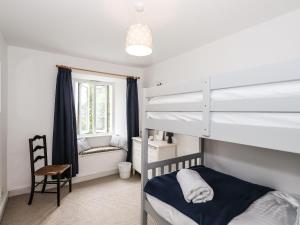 a bedroom with two bunk beds and a chair at Hilber Cottage in Ambleside