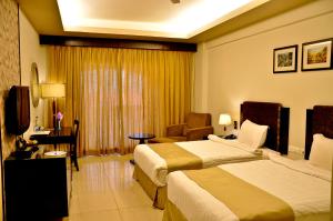 una camera d'albergo con due letti e una sedia di Pramod Convention & Club Resort a Cuttack