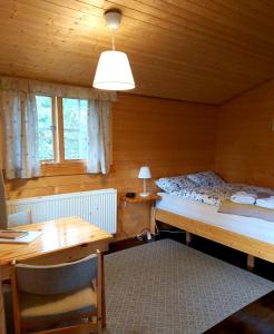 a bedroom with two beds and a desk and a table at Bakkakot 3 Cozy Cabin In The Woods in Akureyri