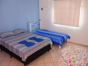 a bedroom with two beds with blue sheets and a window at Pousada Ikaro in Guarapari