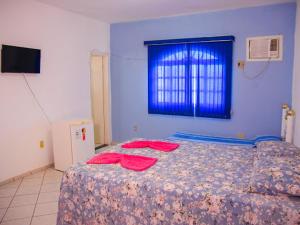 a bedroom with a bed with red sheets and a window at Pousada Ikaro in Guarapari