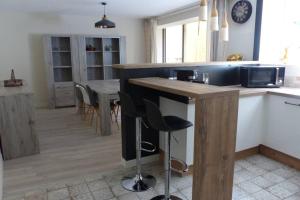 - une cuisine avec un bar avec des tabourets et une table dans l'établissement Le Romarin, à Beaumes-de-Venise