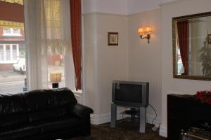 a living room with a black leather couch and a television at Beachcomber Hotel in Blackpool