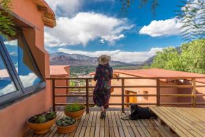 a woman standing on a balcony with a dog at Villa del Cielo in Tilcara