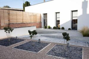 two potted trees in the courtyard of a house at Le Clos du fond Cailloux - Gîte 2 à 7 personnes in Longuenesse