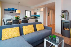 ハイリゲンハーフェンにあるOstsee - Maisonette - Appartement Nr 53 "Schöne Aussicht" im Strand Resortの青いソファ(黄色の枕付)が備わるリビングルーム