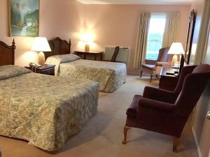 a hotel room with two beds and a chair at Rollo Bay Inn in Souris