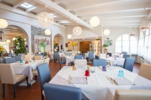 un restaurante con mesas blancas y sillas azules en Hotel Antica Stallera, en Cannobio