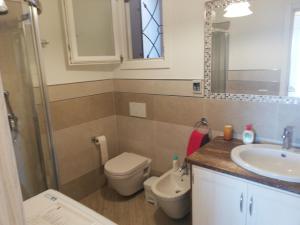 ein Badezimmer mit einem Waschbecken, einem WC und einem Spiegel in der Unterkunft Appartamento Belvedere in Castelsardo