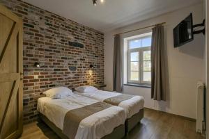 een slaapkamer met een bed met een bakstenen muur bij Domein Warandehof in Gooik