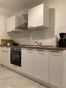 cocina con armarios blancos y horno en Ferienwohnung Sonnenblick en Hohnstein